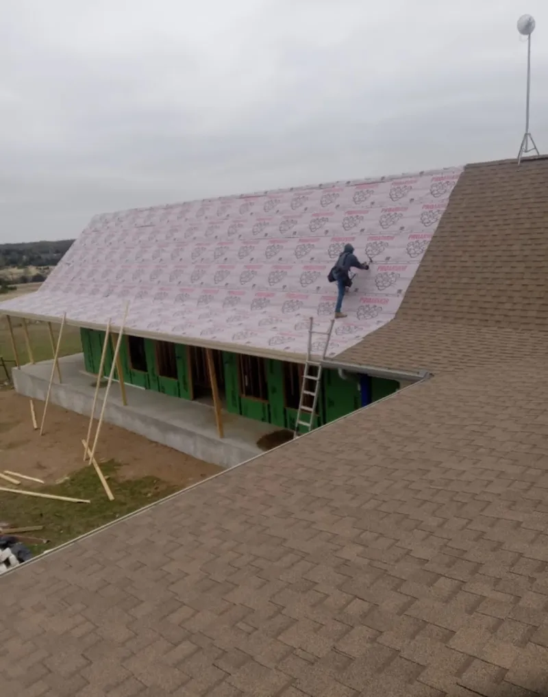 Worker preparing underlayment for a metal roof installation in Parkville